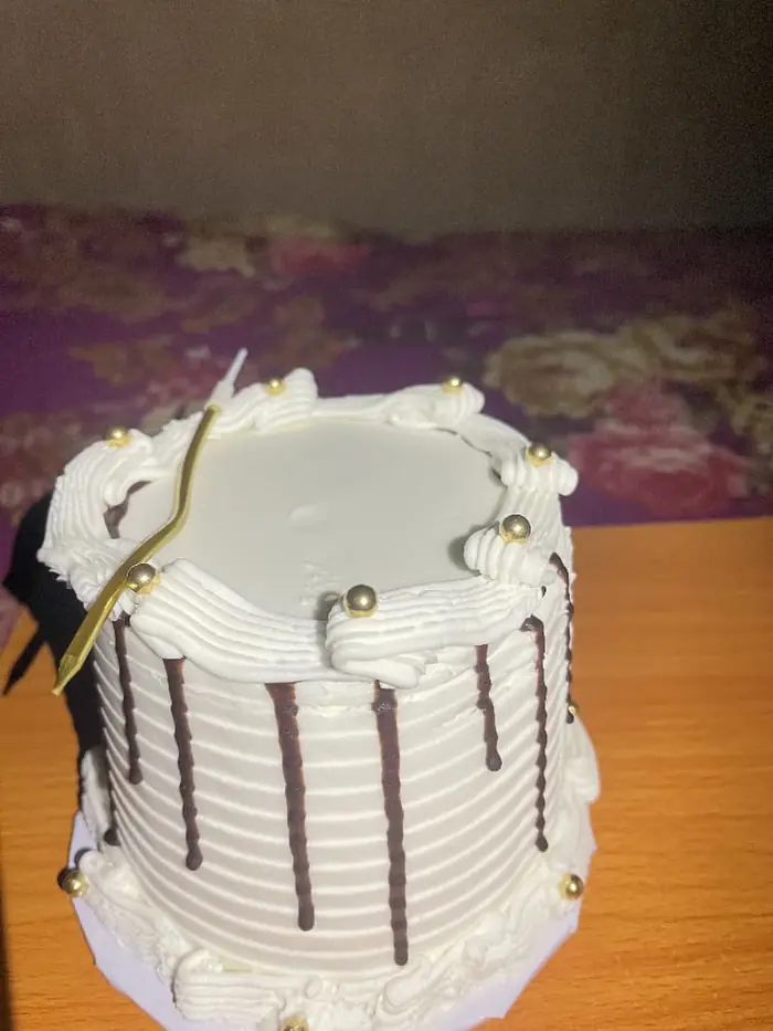 White mini cake with chocolate stripes and gold pearls